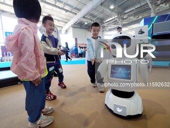 A child watches a humanoid robot dance during the 2024 National Science Popularization Day in Beijing, China, on September 21, 2024. (