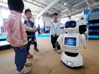 A child watches a humanoid robot dance during the 2024 National Science Popularization Day in Beijing, China, on September 21, 2024. (