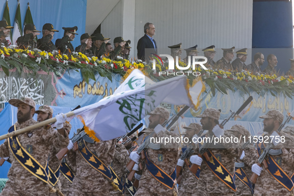 Iranian President Masoud Pezeshkian stands at attention while armed military personnel from the Islamic Revolutionary Guard Corps parade dur...