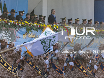 Iranian President Masoud Pezeshkian stands at attention while armed military personnel from the Islamic Revolutionary Guard Corps parade dur...