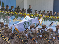 Iranian President Masoud Pezeshkian stands at attention while armed military personnel from the Islamic Revolutionary Guard Corps parade dur...