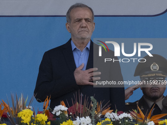 Iranian President Masoud Pezeshkian (C) stands at attention while attending a military parade commemorating the anniversary of the Iran-Iraq...