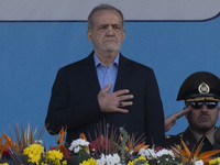 Iranian President Masoud Pezeshkian (C) stands at attention while attending a military parade commemorating the anniversary of the Iran-Iraq...