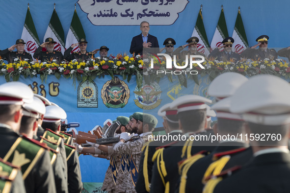 Iranian President Masoud Pezeshkian stands at attention while armed military personnel from the Islamic Revolutionary Guard Corps parade dur...