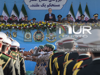 Iranian President Masoud Pezeshkian stands at attention while armed military personnel from the Islamic Revolutionary Guard Corps parade dur...