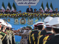 Iranian President Masoud Pezeshkian stands at attention while armed military personnel from the Islamic Revolutionary Guard Corps parade dur...