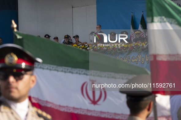 Iranian President Masoud Pezeshkian (C) stands at attention while attending a military parade commemorating the anniversary of the Iran-Iraq...