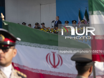 Iranian President Masoud Pezeshkian (C) stands at attention while attending a military parade commemorating the anniversary of the Iran-Iraq...