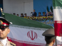 Iranian President Masoud Pezeshkian (C) stands at attention while attending a military parade commemorating the anniversary of the Iran-Iraq...