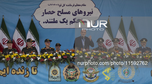 Iranian President Masoud Pezeshkian (C) speaks while standing next to Iranian army and IRGC commanders during a military parade commemoratin...