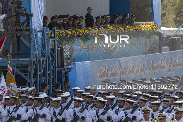 Iranian President Masoud Pezeshkian stands at attention while Iranian Navy military personnel parade during a military parade commemorating...