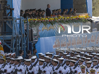 Iranian President Masoud Pezeshkian stands at attention while Iranian Navy military personnel parade during a military parade commemorating...