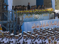 Iranian President Masoud Pezeshkian stands at attention while Iranian Navy military personnel parade during a military parade commemorating...