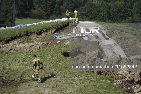 Firefighters inspect the damaged embankment of the Stronie Slaskie dam on the Morawka river in Stronie Slaskie, Poland on September 21, 2024...