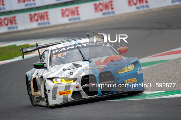 Marco Cassara, Philippe Denes, and Felice Jelmini of the BMW Italia Ceccato Racing team stand by a BMW M4 GT3 GT car on a pit lane during th...