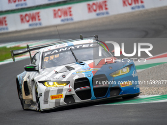 Marco Cassara, Philippe Denes, and Felice Jelmini of the BMW Italia Ceccato Racing team stand by a BMW M4 GT3 GT car on a pit lane during th...