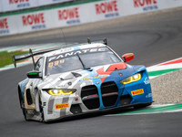 Marco Cassara, Philippe Denes, and Felice Jelmini of the BMW Italia Ceccato Racing team stand by a BMW M4 GT3 GT car on a pit lane during th...