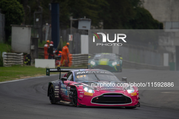 Mex Jansen, Tim Creswick, and Ben Green of the Walkenhorst Motorsport team stand by an Aston Martin Vantage AMR GT3 EVO GT car in the pit la...