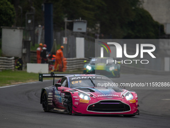 Mex Jansen, Tim Creswick, and Ben Green of the Walkenhorst Motorsport team stand by an Aston Martin Vantage AMR GT3 EVO GT car in the pit la...