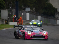 Mex Jansen, Tim Creswick, and Ben Green of the Walkenhorst Motorsport team stand by an Aston Martin Vantage AMR GT3 EVO GT car in the pit la...