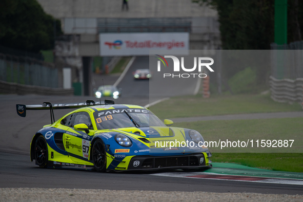 Dennis Marschall, Alexander Fach, and Dustin Blattner of the Rutronik Racing team stand next to a Porsche 911 GT3 R (992) GT car on a pit la...