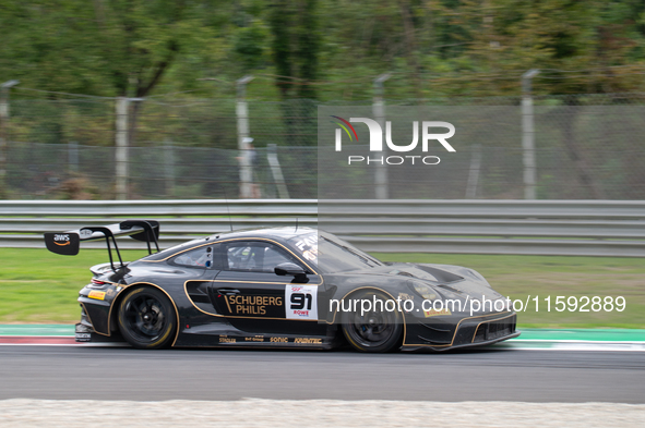 Ralf Bohn, Morris Schuring, and Robert Renauer of team Herberth Motorsport stand next to a Porsche 911 GT3 R (992) GT car on a pit lane duri...