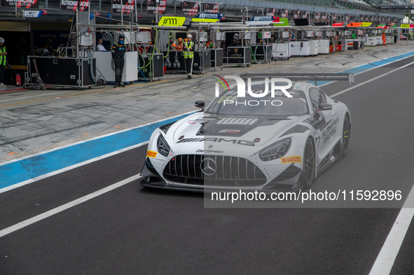 Al Faisal Al Zubair, Dominik Baumann, and Broc Feeney of team Pure Rxcing stand next to a Porsche 911 GT3 R (992) GT car on a pit lane durin...