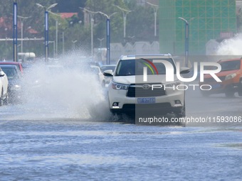 Cars pass a section covered with sea water on Binhai North Road in Yantai, China, on September 21, 2024. (