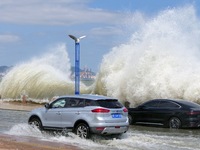 Cars pass a section covered with sea water on Binhai North Road in Yantai, China, on September 21, 2024. (