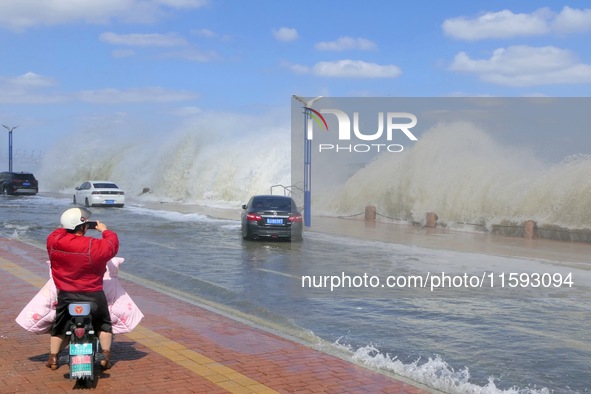 People take photos of waves on Binhai North Road in Yantai, China, on September 21, 2024. 