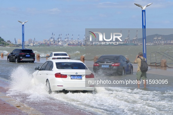 Cars pass a section covered with sea water on Binhai North Road in Yantai, China, on September 21, 2024. 