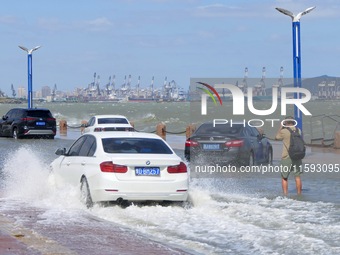 Cars pass a section covered with sea water on Binhai North Road in Yantai, China, on September 21, 2024. (