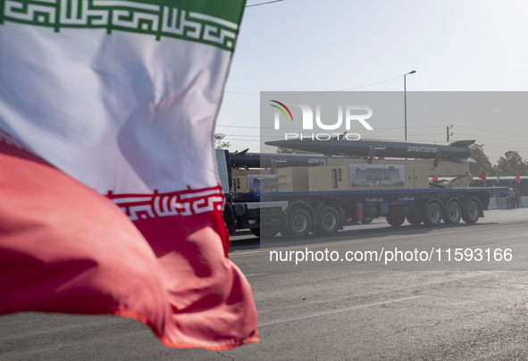 Iran's first-ever hypersonic missile, Fattah, is carried past an Iranian flag by a truck during a military parade commemorating the annivers...