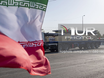 Iran's first-ever hypersonic missile, Fattah, is carried past an Iranian flag by a truck during a military parade commemorating the annivers...