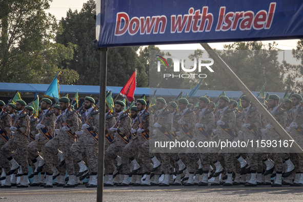 Islamic Revolutionary Guard Corps (IRGC) military personnel march under an anti-Israeli banner in a military parade commemorating the annive...