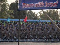 Islamic Revolutionary Guard Corps (IRGC) military personnel march under an anti-Israeli banner in a military parade commemorating the annive...