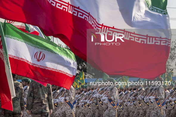 Islamic Revolutionary Guard Corps (IRGC) military personnel march under Iranian flags in a military parade commemorating the anniversary of...