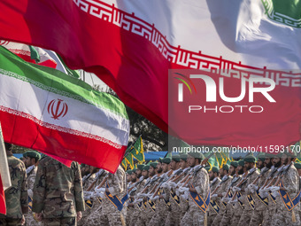 Islamic Revolutionary Guard Corps (IRGC) military personnel march under Iranian flags in a military parade commemorating the anniversary of...