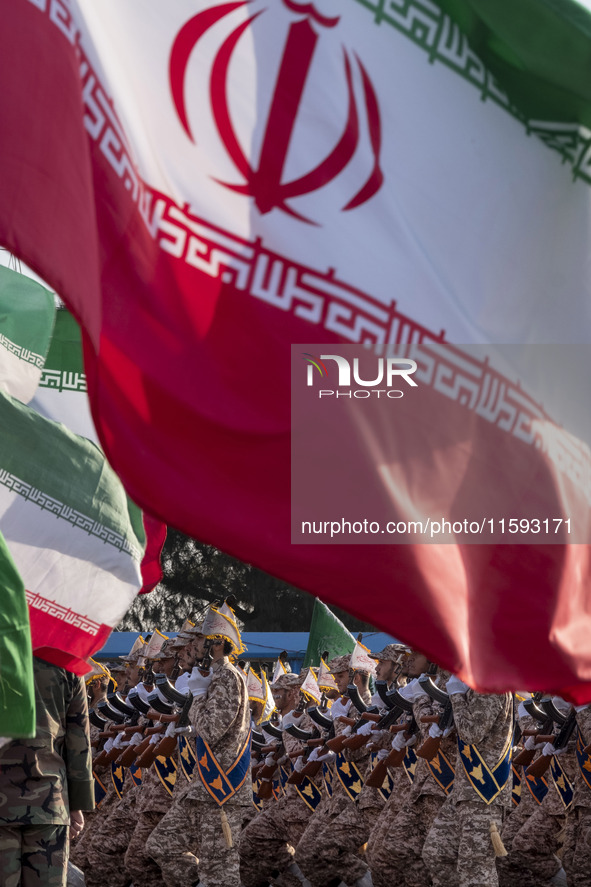 Islamic Revolutionary Guard Corps (IRGC) military personnel march under Iranian flags in a military parade commemorating the anniversary of...