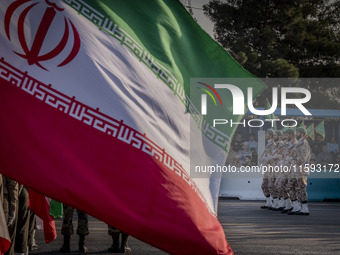 Islamic Revolutionary Guard Corps (IRGC) military personnel march next to an Iranian flag in a military parade commemorating the anniversary...