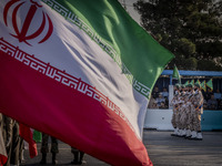 Islamic Revolutionary Guard Corps (IRGC) military personnel march next to an Iranian flag in a military parade commemorating the anniversary...