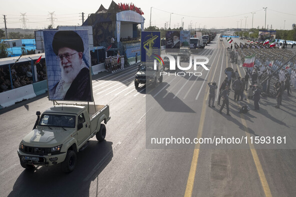 Portraits of Iran's Supreme Leader, Ayatollah Ali Khamenei, and a badge of the Islamic Revolutionary Guard Corps (IRGC), are carried by mili...