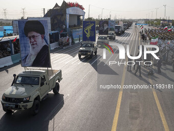 Portraits of Iran's Supreme Leader, Ayatollah Ali Khamenei, and a badge of the Islamic Revolutionary Guard Corps (IRGC), are carried by mili...