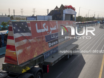 A truck carries a giant anti-U.S. banner during a military parade commemorating the anniversary of the Iran-Iraq War (1980-88) outside the K...