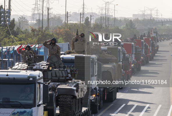 Military personnel of the Islamic Revolutionary Guard Corps (IRGC) salute while standing on tanks during a military parade commemorating the...