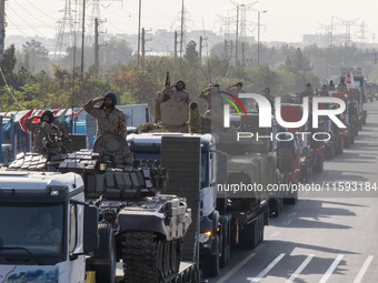 Military personnel of the Islamic Revolutionary Guard Corps (IRGC) salute while standing on tanks during a military parade commemorating the...