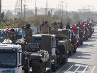 Military personnel of the Islamic Revolutionary Guard Corps (IRGC) salute while standing on tanks during a military parade commemorating the...