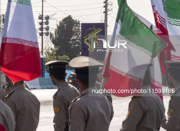 Members of the Iranian Army's land force look at a badge of the Islamic Revolutionary Guard Corps (IRGC), carried by a vehicle, during a mil...