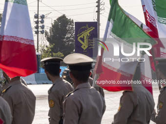 Members of the Iranian Army's land force look at a badge of the Islamic Revolutionary Guard Corps (IRGC), carried by a vehicle, during a mil...