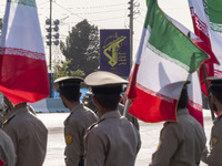 Members of the Iranian Army's land force look at a badge of the Islamic Revolutionary Guard Corps (IRGC), carried by a vehicle, during a mil...